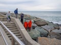 Children on the seashore in winter. Teenagers play on the rocky shore. At the resort in winter. A group of people