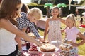 Children Serving On Cake Stall At Busy Summer Garden Fete