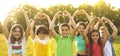 Group of joyful preteen kids standing in sunny park with arms raised show heart shape made by hands Royalty Free Stock Photo