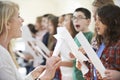 Children In Singing Group Being Encouraged By Teacher