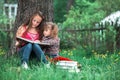 Children sisters reading the book in the summer park.