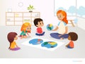 Children sit around world map and redhead female teacher demonstrates them model of planet Earth. Geography lesson Royalty Free Stock Photo