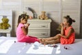 Children sit on bed with lipstick, nail polish and mirror