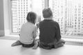 children sit on floor by window and admire view during quarantine. little blond boy and girl with pigtails looking at something Royalty Free Stock Photo