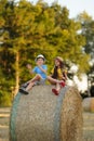 Children sit on a haystack and clap their hands cheerfully, a boy and a girl have fun in nature, cheerful teenagers love Royalty Free Stock Photo