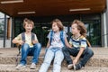 Children sit on the steps of the school and talk. Schoolchildren rest during recess or after school and communicate with Royalty Free Stock Photo