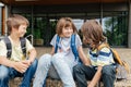 Children sit on the steps of the school and talk. Schoolchildren rest during recess or after school and communicate with Royalty Free Stock Photo