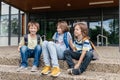 Children sit on the steps of the school and talk. Schoolchildren rest during recess or after school and communicate with Royalty Free Stock Photo