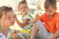 Children sitting on beach and eating lollipops Royalty Free Stock Photo