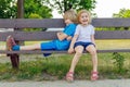 Children sitting on a bench in park in summer. Kids having fun. Friends playing outdoors. Royalty Free Stock Photo