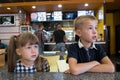 Children sitting in fast food restaurant behind empty table waiting for food Royalty Free Stock Photo