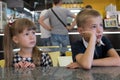 Children sitting in fast food restaurant behind empty table waiting for food Royalty Free Stock Photo