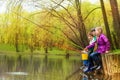 Children sitting and fishing together near pond Royalty Free Stock Photo