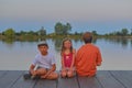 Children sitting on pier. Siblings. Three children of different age - teenager boy, elementary age boy and preschool girl sitting