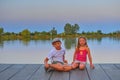 Children sitting on pier. Siblings. Two children of different age - elementary age boy and preschool girl sitting on a wooden pier