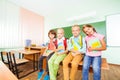 Children sitting in row on desk with textbooks