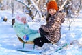 Children sitting on sledge in the winter forest and playing, bright sunlight and shadows on the snow, beautiful nature Royalty Free Stock Photo