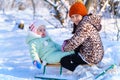 children sitting on sledge in the winter forest and playing  bright sunlight and shadows on the snow  beautiful nature Royalty Free Stock Photo