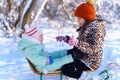 Children sitting on sledge in the winter forest and playing, bright sunlight and shadows on the snow, beautiful nature Royalty Free Stock Photo