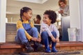 Children Sitting On Step At Home Putting On Boots Before Going On Family Walk With Grandparents Royalty Free Stock Photo