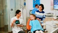 Children sitting on stomatological chair listening pediatric doctor looking on tablet Royalty Free Stock Photo