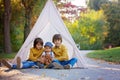 Children, sitting in a tent teepee, holding teddy bear toy with