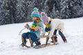 Children sledding, riding a sledge. Children son and daughter play in snow in winter. Outdoor kids fun for vacation. New Royalty Free Stock Photo