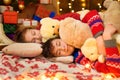 Children sleeping in new year or christmas decoration. Teenage boy and girl. Holiday lights, gifts and christmas tree decorated Royalty Free Stock Photo