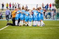 Children soccer football team with coach. Group of kids standing together on the pitch. Coach giving children`s soccer team instru