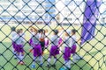 Children soccer team warming on soccer field before a competition match, blurred behind the net for kid sport background and Royalty Free Stock Photo