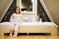 Children in soft warm pajamas playing at wooden cabin home. Concept of childhood, leisure activity, happiness. Brother and sister