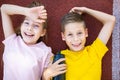 Children sport lifestyle theme. Happy boy and girl teenagers lie joyfully on rubber cover of running track of stadium