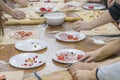 Children`s hands are cutting food for making their first pizza on wooden table. Cooking master class