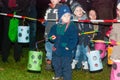 Children stand behind a line holding their lamps