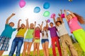 Children stand in semi-circle with balloons up Royalty Free Stock Photo