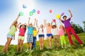 Children standing with arms up to flying balloons Royalty Free Stock Photo