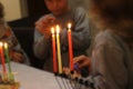 Children standing around the Chanukah menora with lit candles
