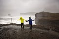 Children, standing at the edge of the ocean on heavy rain day near Dyrholaey, watching the huge waves, Iceland wintertime Royalty Free Stock Photo