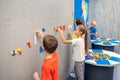 Children standing near wall making mosaic of lego