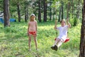 Children summer camp, tourism. children on a summer vacation, swinging on a swing in the forest. children tourist base