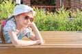 Children and summer. A happy little girl in sunglasses and a hat is laughing and smiling at the camera, lying on a bench Royalty Free Stock Photo