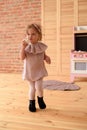 Children and sweets concept. Cute blonde little girl in linen dress eating meringue in play kitchen Royalty Free Stock Photo