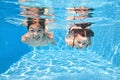 Children swim in swimming pool underwater, little active girls have fun under water, kids sport on family vacation