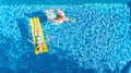 Children in swimming pool aerial drone view fom above, happy kids swim on inflatable ring donut and mattress, girls have fun Royalty Free Stock Photo