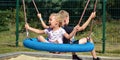 Children on a swing. Boy and girl ride a swing in the park on a summer day. Swing in the children& x27;s amusement park Royalty Free Stock Photo