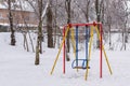 Children swing in park under the snow after the strongest snowfall Royalty Free Stock Photo