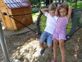 Children swing on a spider-web swing. Boy and girl, brother and sister in the summer on the playground. Swinging the swing. Royalty Free Stock Photo