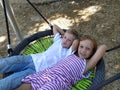 Children swing on a spider-web swing. Boy and girl, brother and sister in the summer on the playground. Swinging the swing Royalty Free Stock Photo