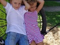 Children swing on a spider-web swing. Boy and girl, brother and sister in the summer on the playground. Swinging the swing. Royalty Free Stock Photo