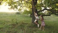 Children swinging on swing on an oak branch in sun. Dreams of flying. concept of happy childhood. Beautiful girls are